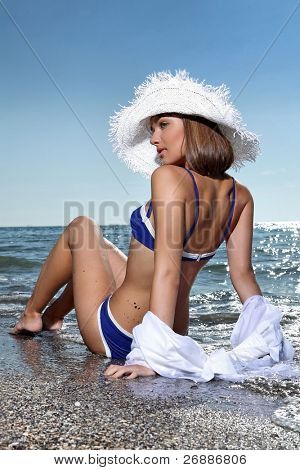 Sexy jovencita descansando en la playa en traje de baño