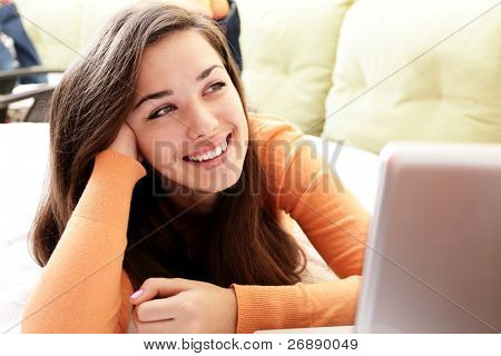 Šťastná dívka ležela v posteli s notebookem