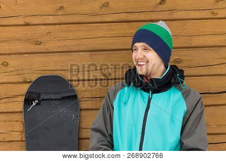 Portrait Man With Snowboard And Hat And Splitboard Near Wooden Wall