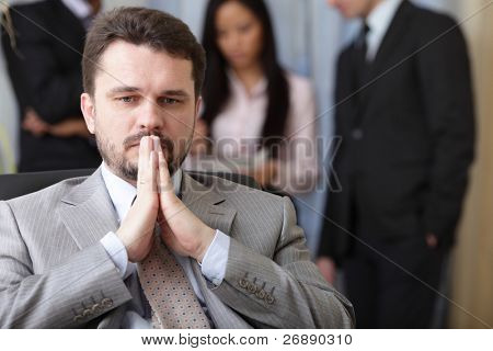 Portrait of a worried businessman with his team working behind