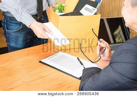 Hand Of A Businessman Hands Over A Resignation Letter Final Remuneration To Executive Boss On A Wood