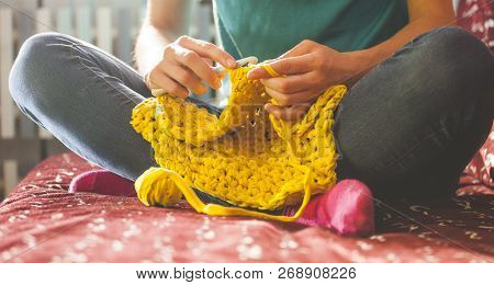 Woman Knits Crochet. The Girl Sits On The Couch And Knits From Knitting Yarn. Crochet Thick Threads.