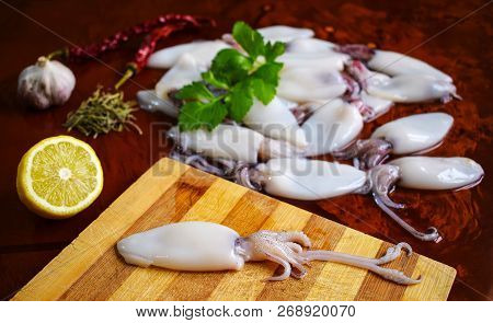 Fresh Calamari. Squid. Seafood, Lemon, Garlic, Pepper, Parsley. Cutting Board.