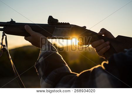 Rifle Hunter Silhouetted In Beautiful Sunset. Cartridges Shotgun. Pulled The Trigger Of The Shotgun
