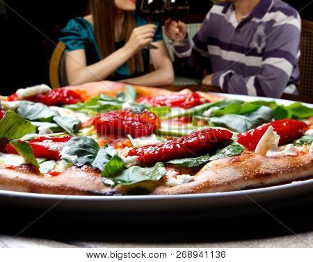 Pizza with dried tomatoes, rucula and mozzarella in pizzeria