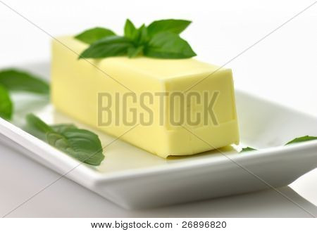 frische Butter Stock auf einem weißen Teller mit Basilikum, hautnah