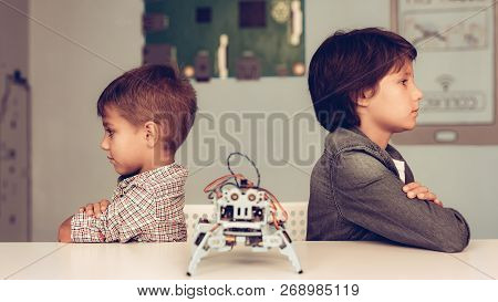 Two Boys Sitting At Table And Constructing Robot. Young Boy In Shirt. Indoor Joy. Modern Hobby Conce