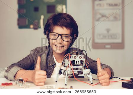 Boy Sitting At Desk And Constructing Robot At Home. Young Boy In Shirt. Indoor Joy. Modern Hobby Con