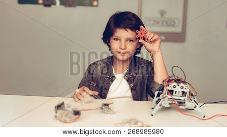 Boy Sitting At Desk And Constructing Robot At Home. Young Boy In Shirt. Indoor Joy. Modern Hobby Con