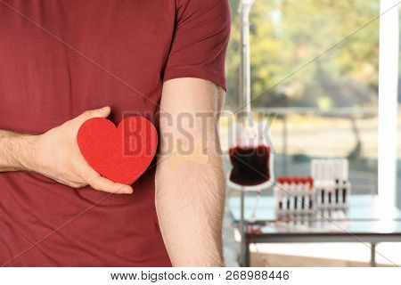 Man Holding Heart Near Hand With Adhesive Plasters At Hospital, Closeup. Blood Donation Concept