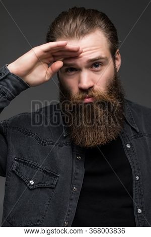 Young Hipster Man With Long Perfect Beard Looking Far Away On Gray Background