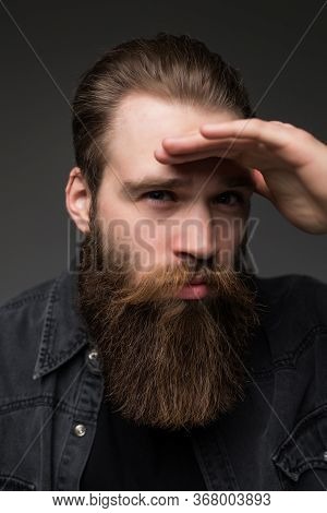 Young Hipster Man With Long Perfect Beard Looking Far Away On Gray Background
