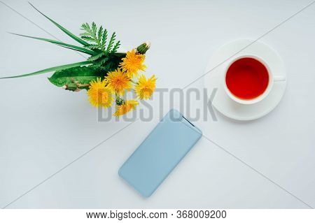 Morning Tea With Light Blue Mobile Phone, Bouquet Of Yellow Spring Dandelion Flowers. Beautifully St