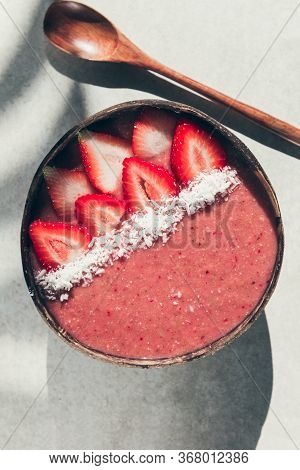 Pink Smoothie From Banana And Strawberries With Pieces Of Strawberries And Coconut Shreds On Top In 