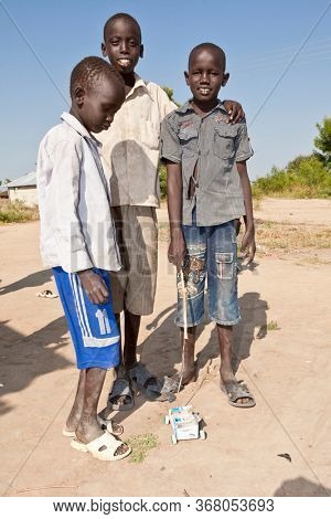 BOR, SOUTH SUDAN-DECEMBER 3, 2010: Young boys play with home made toys while wearing tattered clothing in the village of Bor, South Sudan.