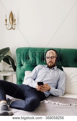 Young Man Lying On Bed At Home, Listening To Music Through Headphones Eyes Closed.