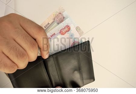 Uae National Currency. Money Banknotes. Man In White T Shirt Put Dirham Banknotes Into Black Wallet.
