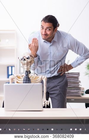 Young male employee and skeleton in the office