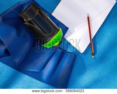 Healthy Lifestyle Concept. Karemat, Sports Bottle, Rubber Tape And Notebook With Pencil