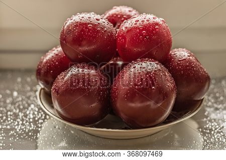 Satsuma Red Plum On A Plate With Water Droplets