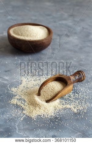 Raw Uncooked Fonio Seeds With A Spoon In A Bowl On Grey Background Close Up