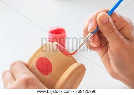 A Child Paints A Wooden Blank Of A Nesting Doll. Children's Crafts