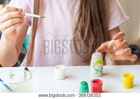 A Child Paints A Wooden Blank Of A Nesting Doll. Children's Crafts
