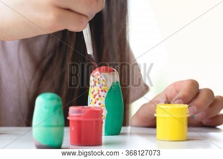 A Child Paints A Wooden Blank Of A Nesting Doll. Children's Crafts