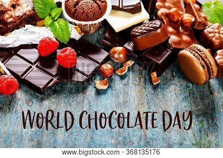 World Chocolate Day concept. An assortment of white, dark, and milk chocolate with nuts, muffins, macaroons - on wooden background