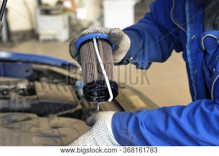 Car Repair At A Service Station. A Professional Mechanic Is Holding A Old Engine Fuel Filter For Rep