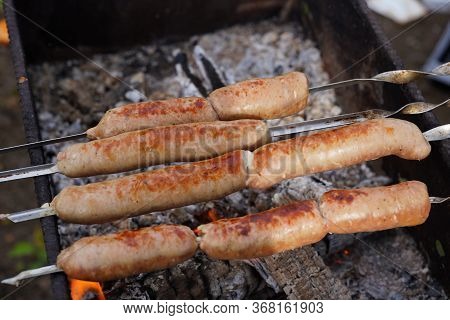 Close Up Of Toasted Sausages On Skewers. Succulent Kupaty Roasting On Chargrill. Concept Of Picnic O
