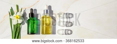 Homeopathic Oil, Serum And Bottles With Plants Onon Marble Background. Concept Of Natural Organic Co