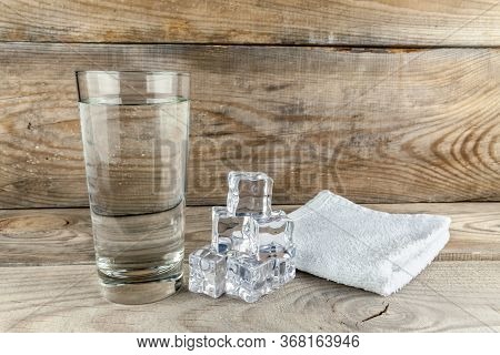 Glass With Foda, Next To Ice Cubes And A Towel Layer On A Wooden Background.