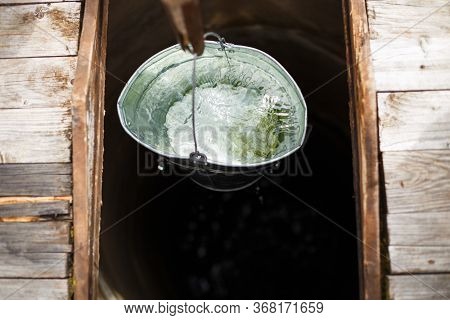 Blue Bucked Inside Water Well. A Water Well With An Old Iron Bucket