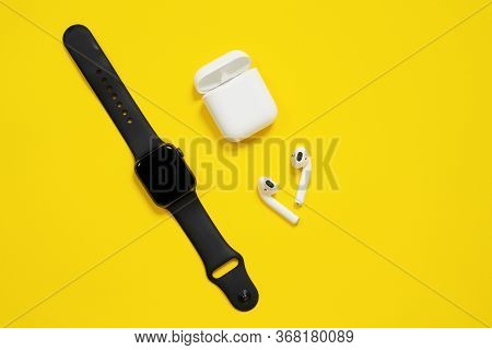 May 01, 2020, Rostov, Russia: Black Applewatch And White Airpods With Box On Bright Yellow Backgroun