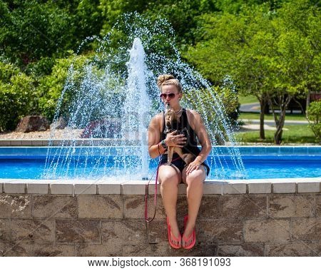 A Woman And Her Dog Siting On A Fountains Edge