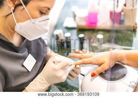 A Worker With Security Measures And A Face Mask Painting Colored Nails Of The Client. Reopening Afte