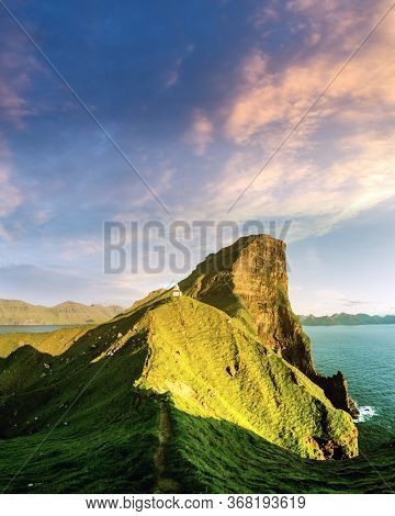 Incredible sunset landscape with Kallur lighthouse on green hills of Kalsoy island, Faroe islands, Denmark