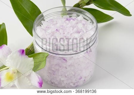 Transparent Plastic Jar With Large Flakes Of Violet Lavender Sea Salt And Natural Fresh Orchid Flowe