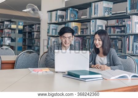 High School Or College Students Studying And Reading Together In Library. Student Use Laptop At Libr