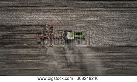 Aerial View Of A Clean Field In Which The Tractor Makes Vertical Tillage. Red Tillage Equipment And 