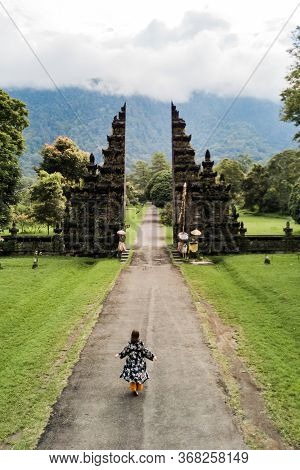 Tourist Woman Walking Through The Balinese Gate Candi Bentar. Vacation On Bali. Aerial View From Dro
