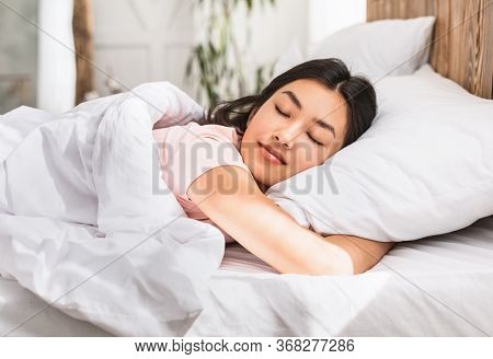 Healthy Sleep. Relaxed Asian Girl Sleeping Hugging Pillow Resting Lying In Comfortable Bed At Home.