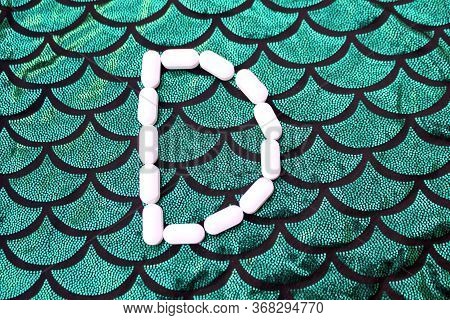Alphabet Made Of Pills On A Green And Black Background. Vitamins On A Background Of Scales. Abc From