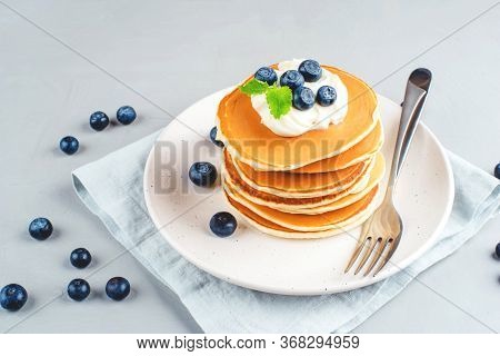 A Stack Of Pancakes With Fresh Blueberries And Cheesecream.