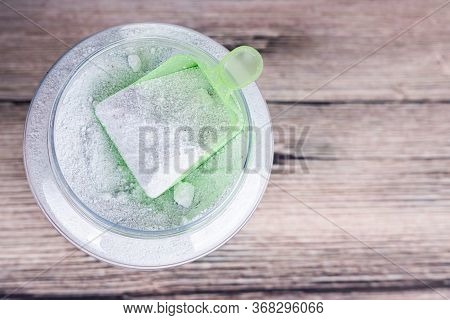 Overhead View Of Scooper Containing Laundry Powder Detergent On Wooden Surface