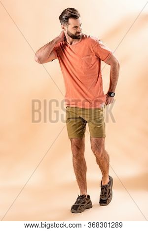 Stylish Handsome Man Posing In Shorts And Summer T-shirt On Beige