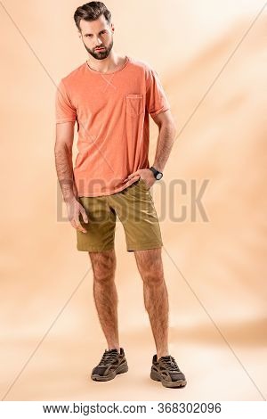 Stylish Man Posing In Shorts And Summer T-shirt On Beige