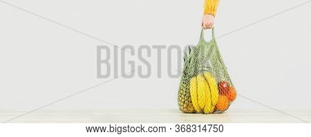 Delivery Of Grocery. Hand Holds Mesh Shoper Bag With Fresh Fruit And Vegetables Green Produce. Eco F