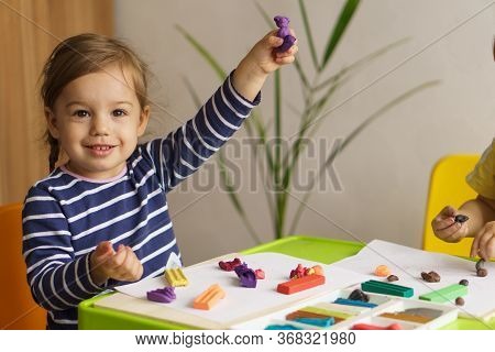 Little Girl Playing With Plasticine On A Table In The Nursery Sitting. Plasticine Molding. Developme
